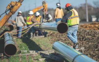 Workers in protective gear extending a gas pipeline.